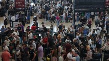 Travelers wait at check-in counters at Berlin Airport during an IT outage that has disrupted airline services here and worldwide on July 19, 2024 in Schoenefeld, Germany. Businesses, travel companies and Microsoft users across the globe were among those affected by a tech outage today. 