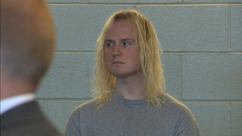 A shot of a man with shoulder length blonde hair wearing a gray t-shirt