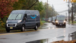 Trucks travel through a flooded road while exiting from an Amazon delivery station in Carlstadt, New Jersey, U.S., on Tuesday, Oct. 13, 2020. 