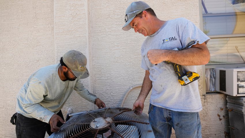 Owner of Total Refrigeration, and service tech Michael Villa, left, work on replacing a fan motor on an air conditioning