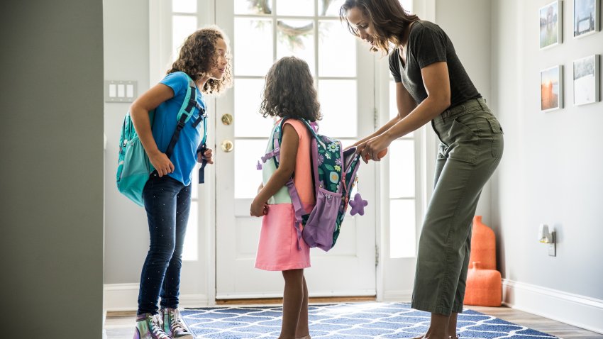 Mother packing daughters backpacks for school