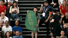 TOPSHOT - A security member stands behind a fan holding a sign depicting the shape of the island of Taiwan with a caption reading "come on Taiwan" in the audience during the men's doubles badminton semi-final match between Denmark and Taiwan in the Paris 2024 Olympic Games at Porte de la Chapelle Arena in Paris on August 2, 2024. (Photo by Arun SANKAR / AFP) (Photo by ARUN SANKAR/AFP via Getty Images)