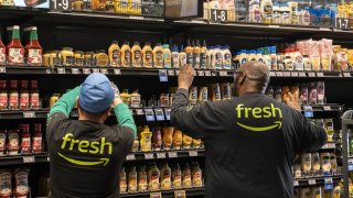 Workers stock shelves at an Amazon Fresh grocery store in Seattle, Washington, US, on Thursday, May 2, 2024. 