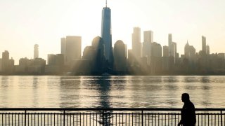 The sun rises behind the skyline of lower Manhattan and One World Trade Center on September 14, 2024, in Jersey City, New Jersey. 