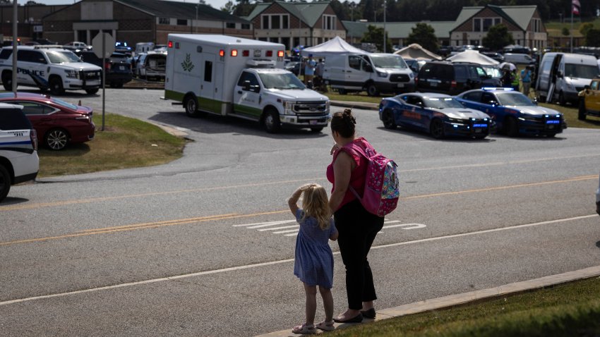 A young girl and her mother watch as law enforcement and first responders surround Apalachee High School