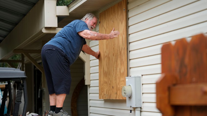 Dave McCurley boards up the windows to his home