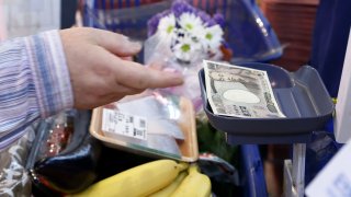 A customer places a Japanese 10,000 yen banknote on a checkout counter while making a purchase at an Akidai YK supermarket in Tokyo, Japan, on Monday, June 27, 2022.