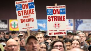 People hold signs during a strike rally for the International Association of Machinists and Aerospace Workers (IAM) at the Seattle Union Hall in Seattle, Washington, on October 15, 2024.