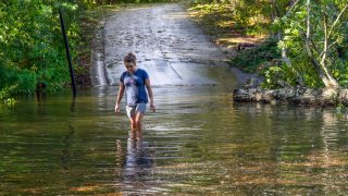 FILE - Teresa Elder walks through a flooded Sandy Cove Drive from Hurricane Helene on Sept. 27, 2024, in Morganton, N.C.