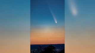 A comet cuts through a blue and orange sky