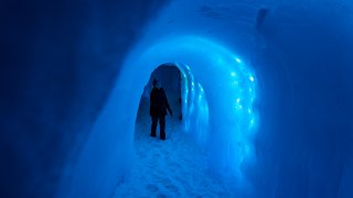 People walk by illuminated ice walls at Ice Castles in North Woodstock, New Hampshire on February 1, 2024.