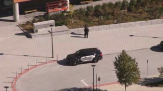 A lone police car sits in a driveway loop outside a high school