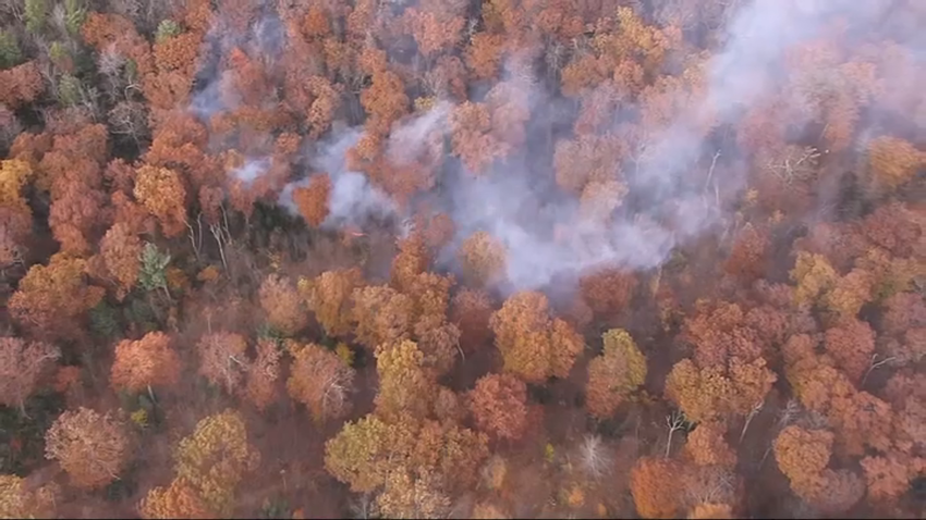 A brush fire burning amid trees that were changing colors in Holden, Massachusetts, on Wednesday, Oct. 23, 2024.