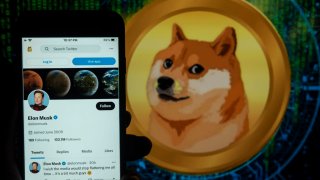 In this photo illustration, the Elon Musk’s twitter account seen displayed on a mobile phone screen with a Dogecoin logo in the background.