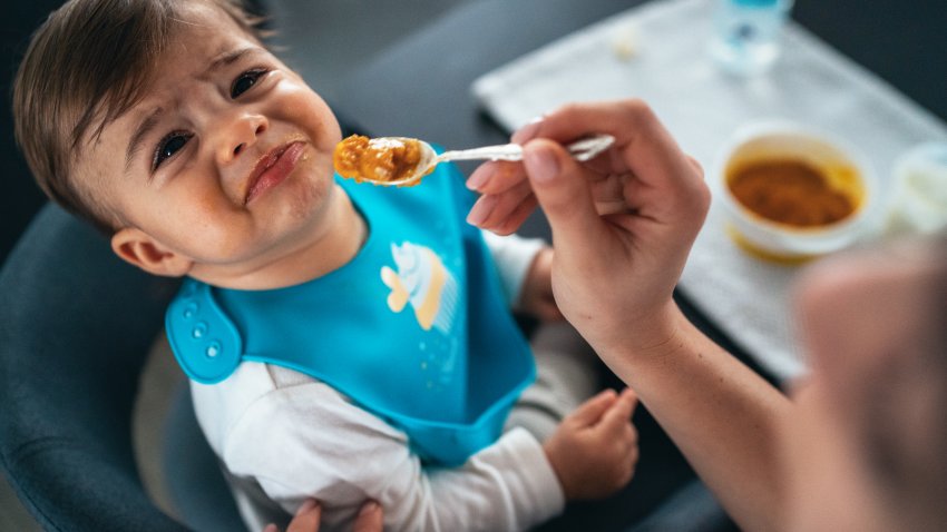 A baby is showing distaste for his food.