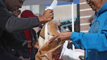 LOS ANGELES, CALIFORNIA - NOVEMBER 20: A Los Angeles police officer passes out free turkeys during the 3rd annual turkey drive at Wilshire Station on November 20, 2023 in Los Angeles, California. The Los Angeles Police Department (L.A.P.D.) gives away 2,000 turkeys and bags of food to families during their 3rd annual turkey drive ahead of the Thanksgiving holiday. (Photo by Justin Sullivan/Getty Images)