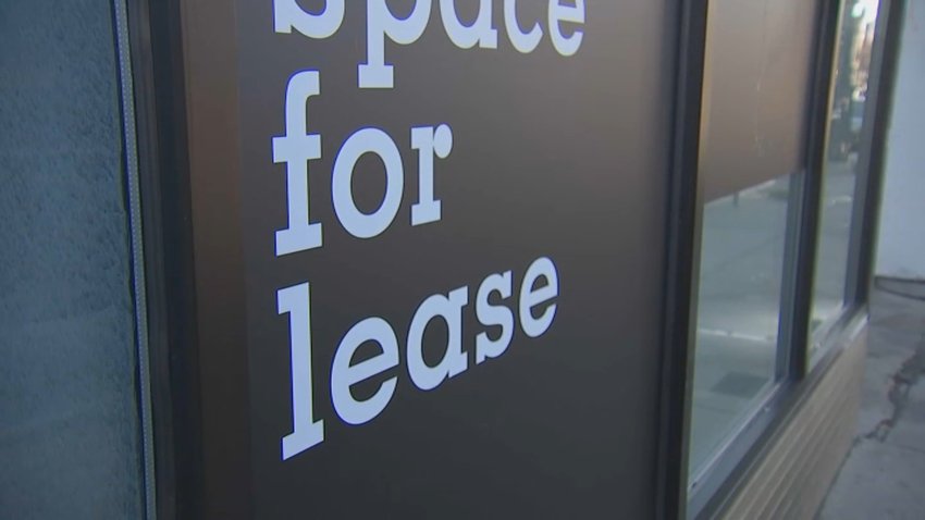 A black sign with white text advertising space for lease