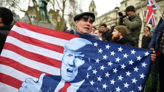 A man holds an American flag depicting president-elect Donald Trump at Parliament Square in London.