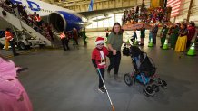 Nine-year-old Rylan Hadad, left, walks with his mother, Eva, during the United Airlines annual "fantasy flight" to a fictional North Pole at Denver International Airport, Saturday, Dec. 14, 2024, in Denver. (AP Photo/David Zalubowski)