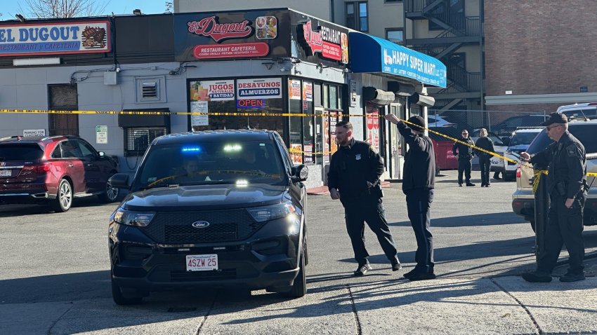 A business with a blue awning and multiple signs is taped off and surrounded by police