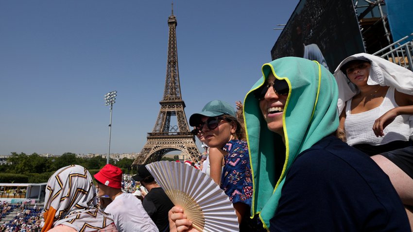 FILE - A fan uses a fan to keep cool in the sweltering heat at Eiffel Tower Stadium during a beach volleyball match between Cuba and Brazil at the 2024 Summer Olympics, July 30, 2024, in Paris, France.