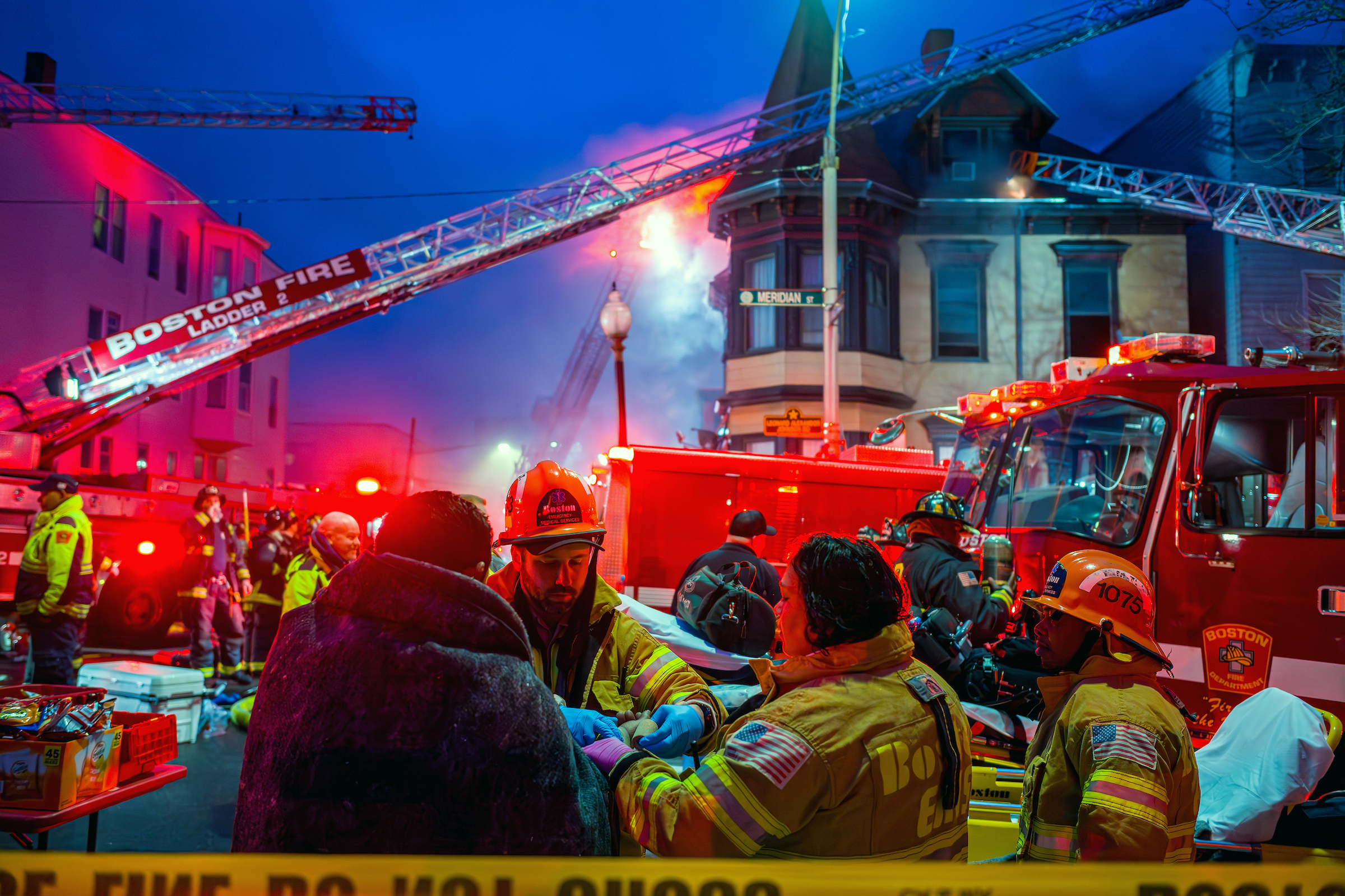 Boston firefighters and Boston EMS render aid at the scene of a large fire on East Boston’s Meridian Street. A 10-year-old girl and an adult perished in the early morning blaze.