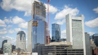 South Station Tower, shown under construction from Fort Point, has signed its first office tenant. The building will open next year.