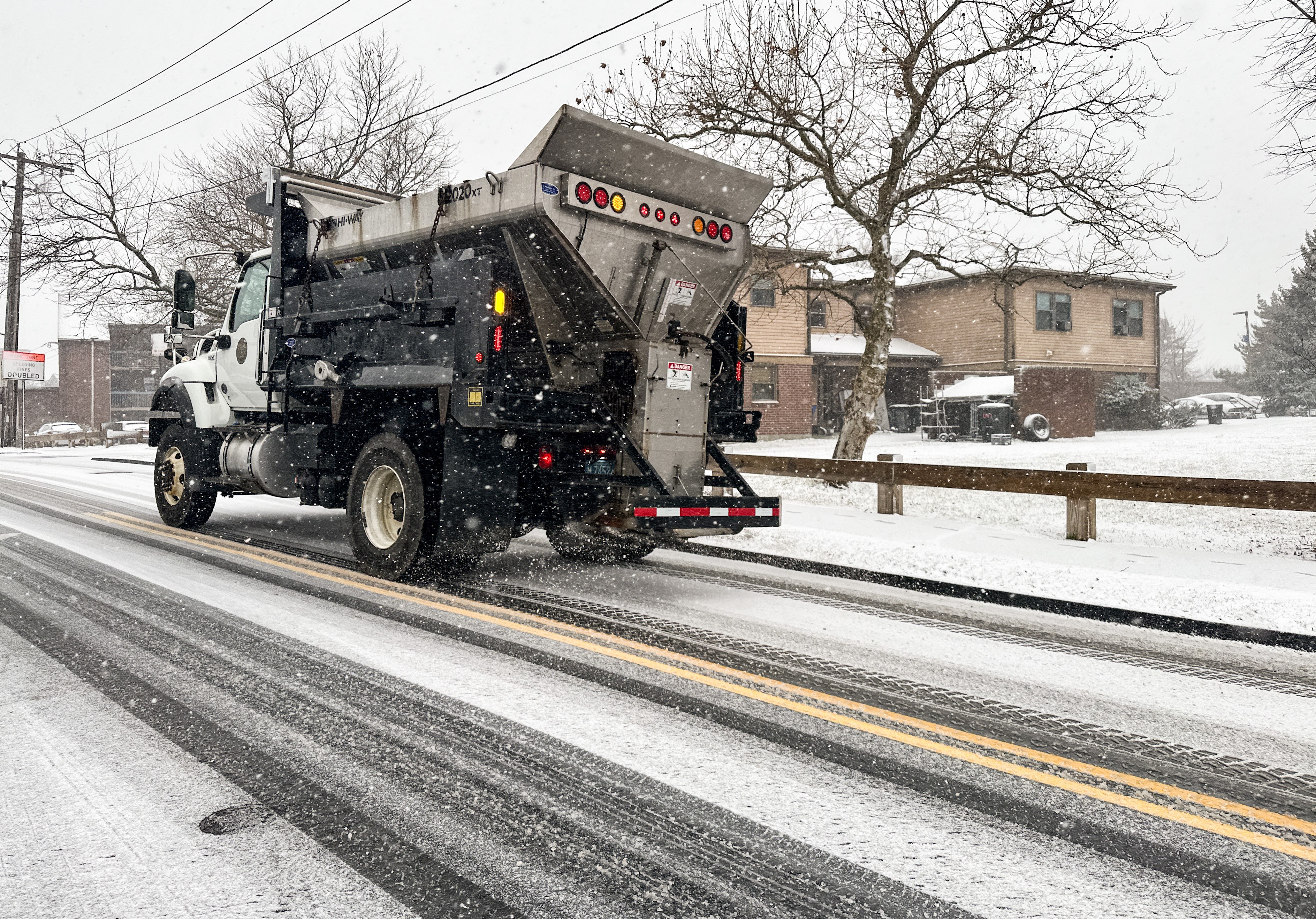 A de-icing truck drives through a snowy street in Winthrop, Massachusetts, on Friday, Dec. 20, 2024.