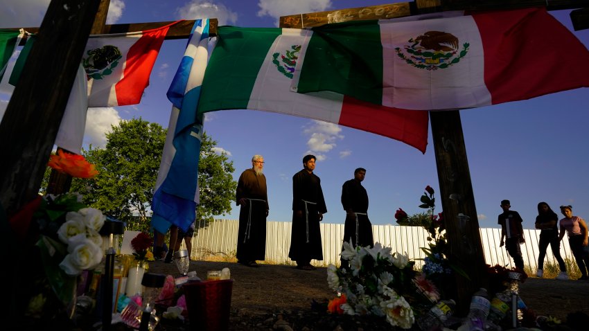 FILE – People visit a makeshift memorial honoring the victims and survivors of a human smuggling tragedy, where dozens of migrants were found in an airless tractor-trailer rig, in San Antonio, July 6, 2022.