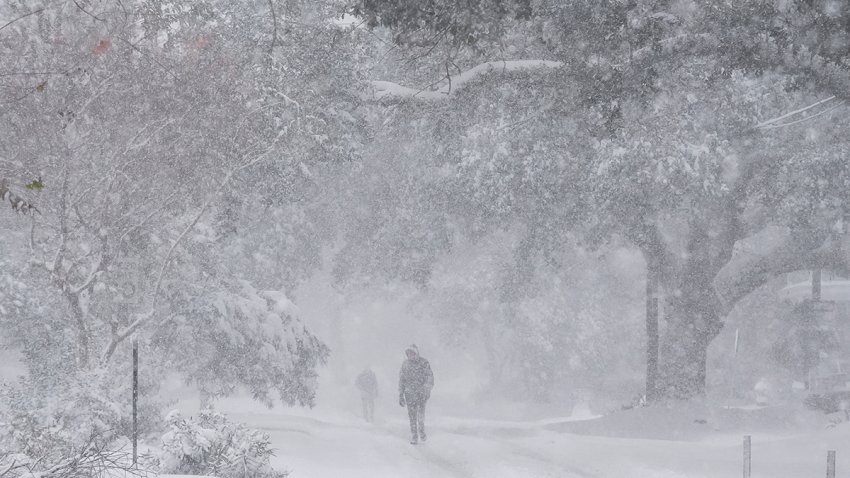 People walk as snow falls in New Orleans, Tuesday, Jan. 21, 2025.